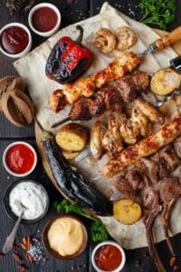 a variety of food on skewers with dipping sauces